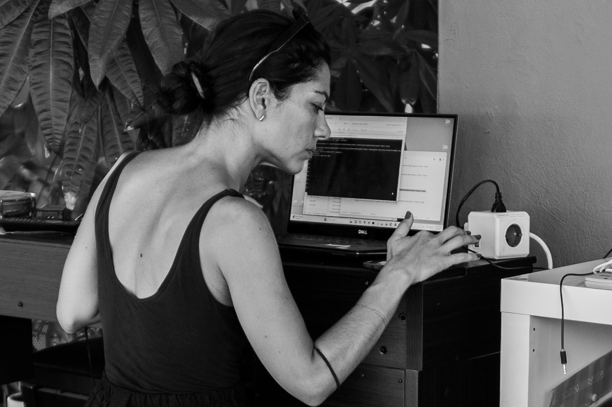 Vilelmini working on a laptop during the workshop, concentrating on technical adjustments.